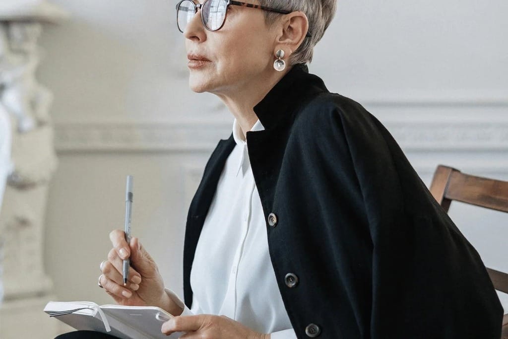 Person in business attire holding a pen and notebook.