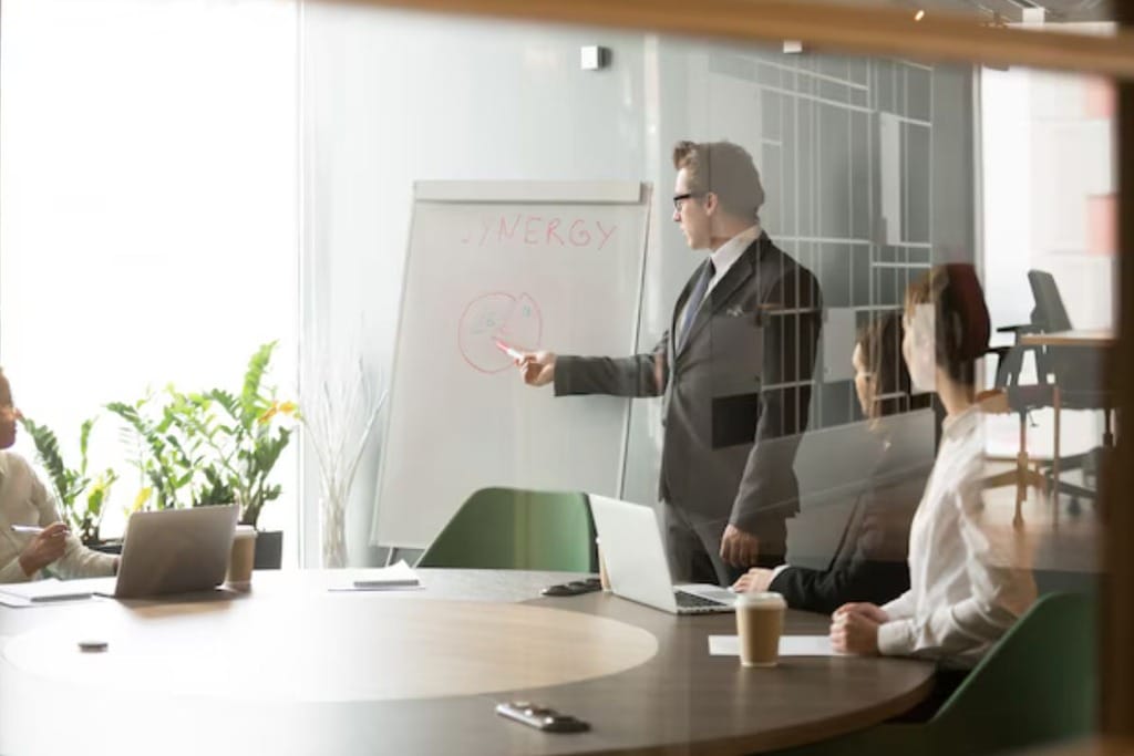 A diverse team collaborating on a presentation, gathered around a computer in a modern, well-lit office.