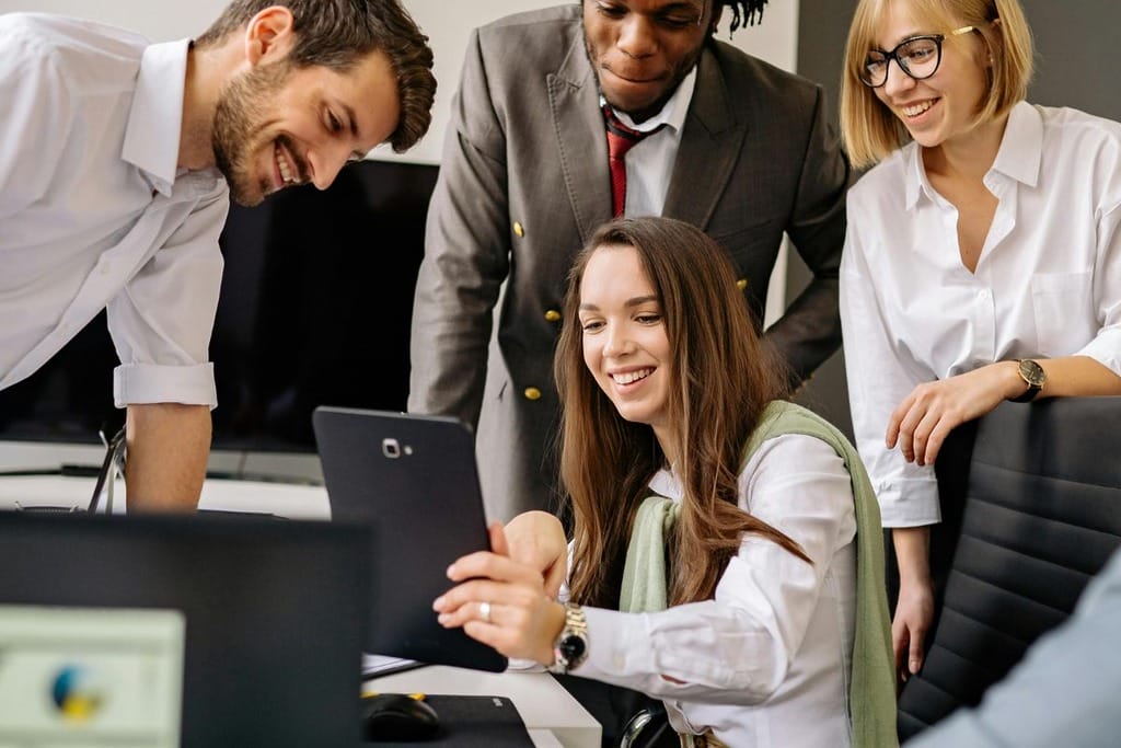 Business professionals in discussion around a table with one holding a tablet.