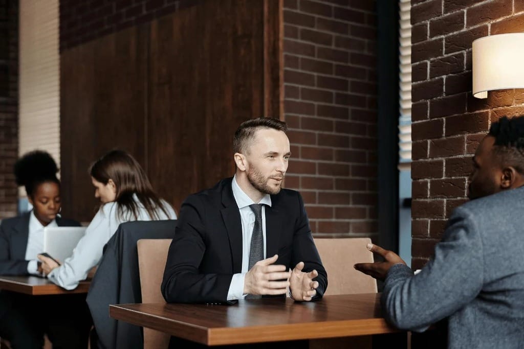 Business people having a discussion at a table in a modern office setting.