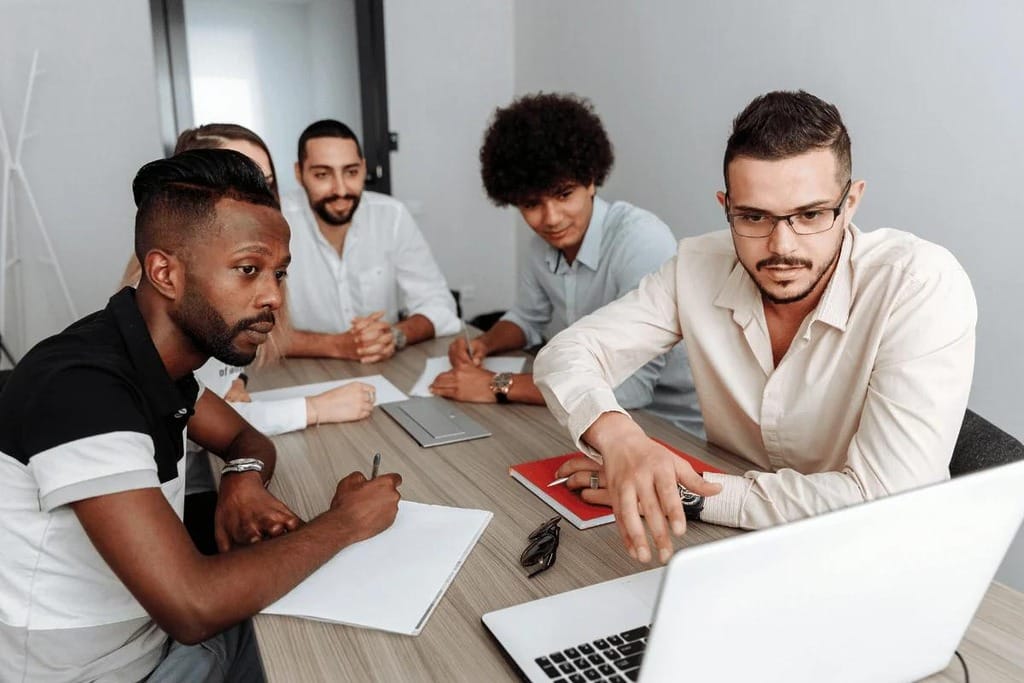Group of professionals engaged in a serious discussion around a laptop.
