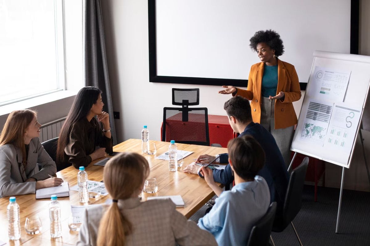 A business presentation with attendees looking towards a speaker and a whiteboard.