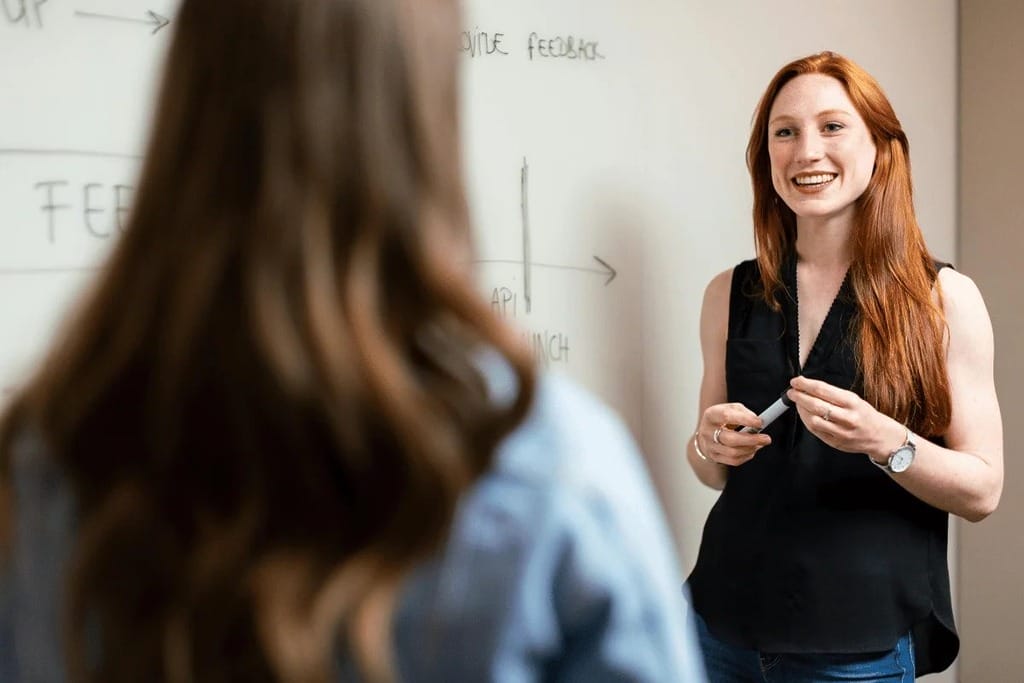 Smiling presenter leading a discussion in front of a whiteboard.
