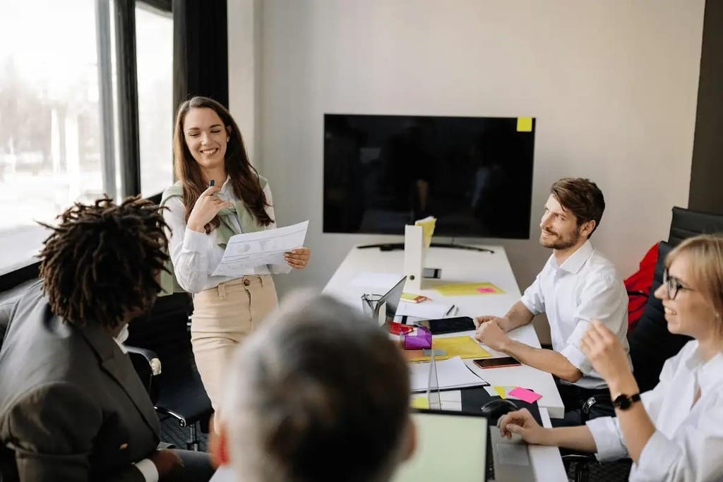 Smiling presenter engaging with her team during a business meeting.