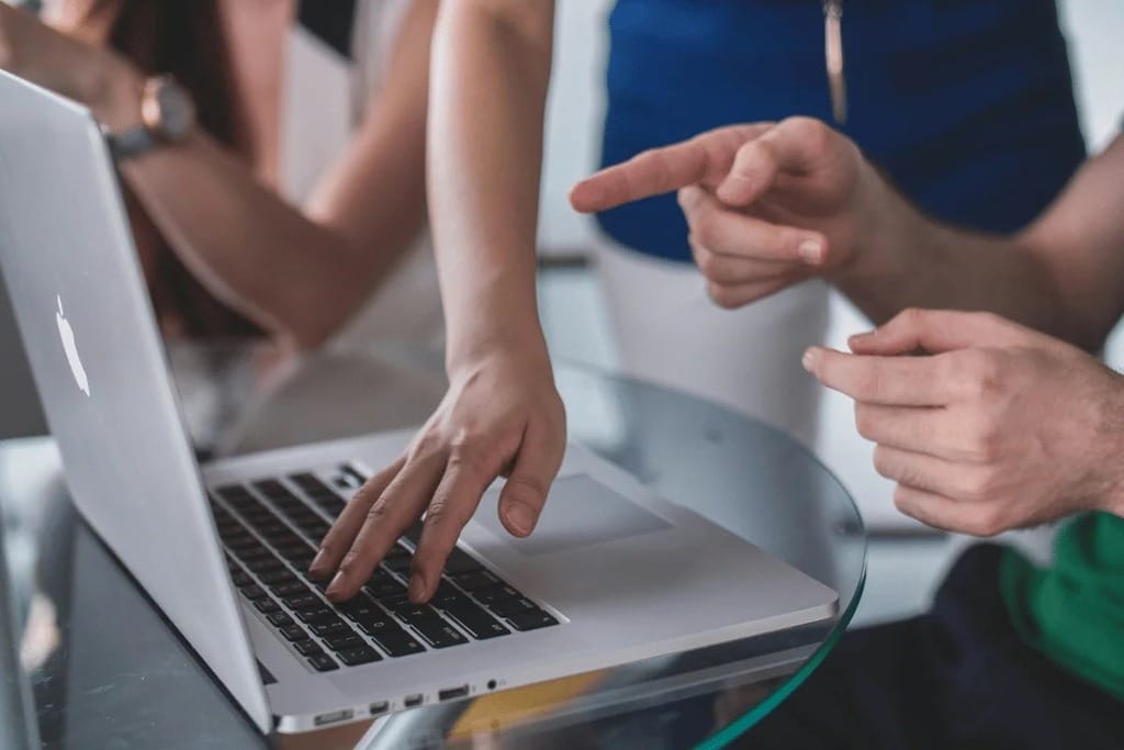 Close-up of hands working on a laptop during a team meeting.