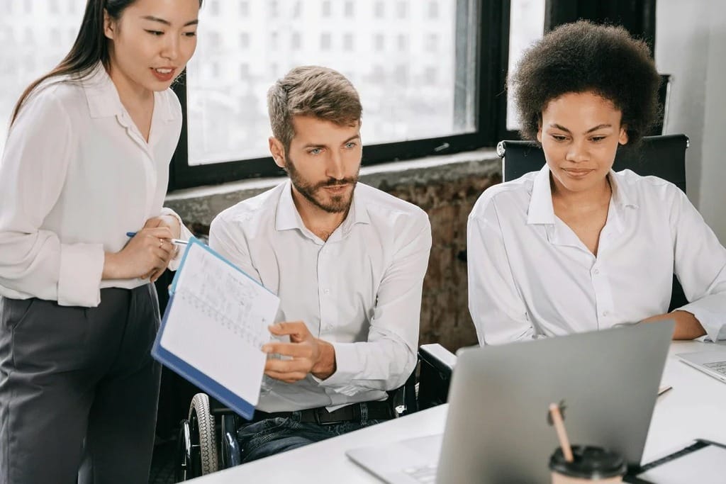Team members in a business meeting, analyzing data on a computer.