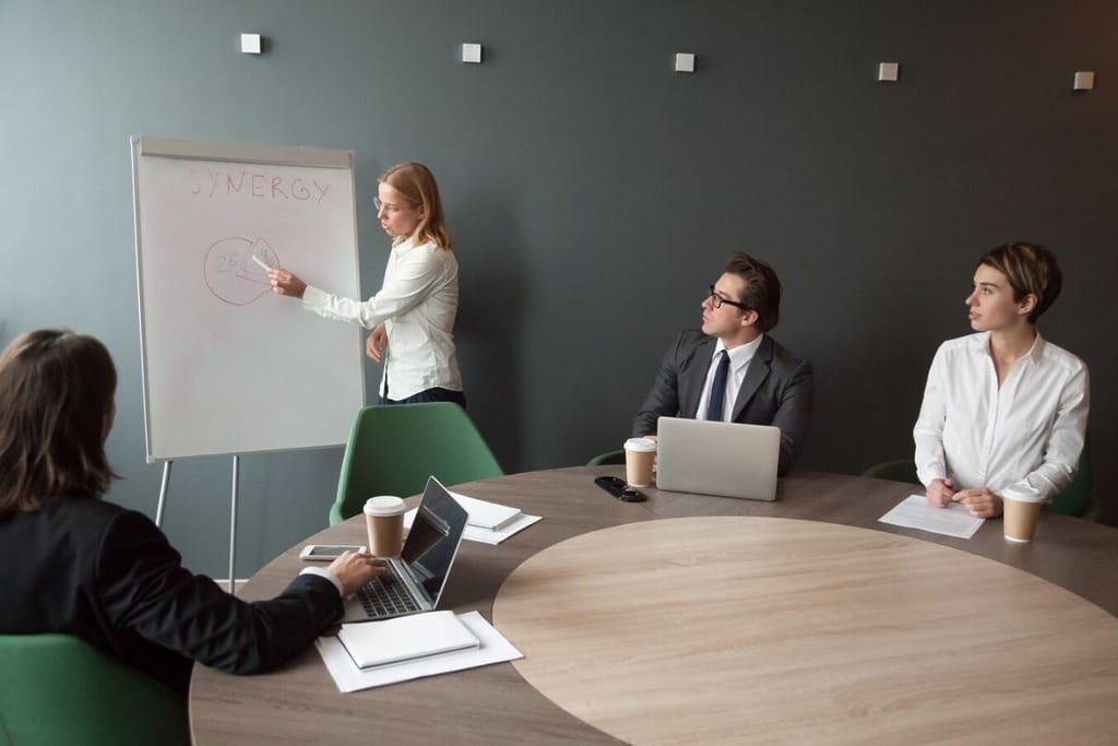 Professional woman explaining a pie chart in a business meeting.
