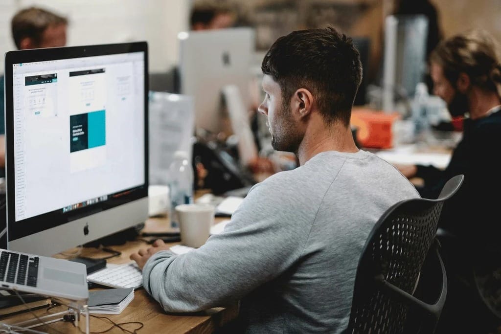 Office worker using a large monitor to work on a graphic design project.