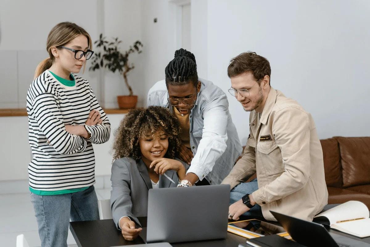 Team members engaged in a discussion while working on a laptop.
